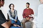 Close up of a young support group during meeting with professional therapist. Group of employees looking serious during a counseling session
