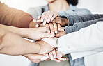 Group of businesspeople stacking their hands in support with their colleagues standing in a meeting in an office at work. Businesspeople piling their hands for motivation and success together