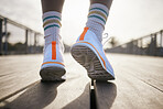 A pair of running shoes being warn. An African American man is moving forward on a beautifully lit walkway