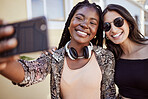 Best friends having fun and taking a selfie outdoors. Two multiethnic female friends spending time together and taking photos for social media on smartphone