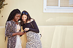 Best friends texting on smartphone while standing on sidewalk.Two multiethnic female friends standing on street and browsing social media while pointing at screen