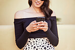 Close up of young woman using smartphone while standing on sidewalk. Stylish woman sending a message on social media or using mobile app while on city street