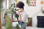 Young focused mixed race businesswoman drinking a cup of coffee while working on a laptop at work. One hispanic female businessperson having a coffee while checking her emails in an office