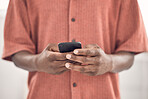 Closeup of a businessman typing a message on a phone at work. One creative male businessperson using social media on his cellphone in an office. Business professional checking his emails on a smartphone