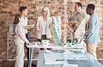 Group of diverse architects discussing plans, blueprints and schematics during a meeting in their office boardroom. Business people brainstorming and planning their upcoming project development