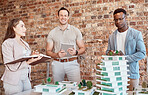 Group of diverse architects discussing plans, blueprints and schematics during a meeting in their office boardroom. Business people brainstorming and planning their upcoming project development