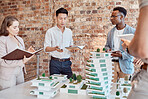 Group of diverse architects discussing plans, blueprints and schematics during a meeting in their office boardroom. Business people brainstorming and planning their upcoming project development