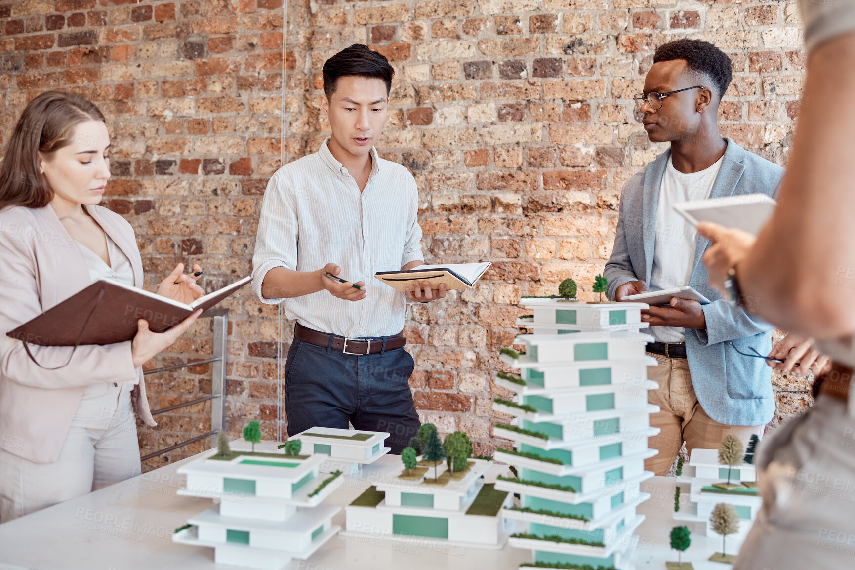 Buy stock photo Man, architect and notebook with team, model and building with ideas, talk and group in office. Person, women and discussion for review, diversity or design for skyscraper with property development