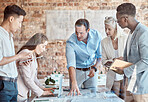 Group of diverse architects discussing plans, blueprints and schematics during a meeting in their office boardroom. Business people brainstorming and planning their upcoming project development