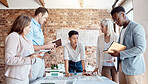 Group of diverse architects discussing plans, blueprints and schematics during a meeting in their office boardroom. Business people brainstorming and planning their upcoming project development