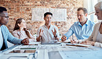 Group of diverse architects discussing plans, blueprints and schematics during a meeting in their office boardroom. Business people brainstorming and planning their upcoming project development