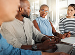 Group of diverse businesspeople having a meeting in an office at work. Business professionals talking while using a laptop together in an office. Businesspeople planning together