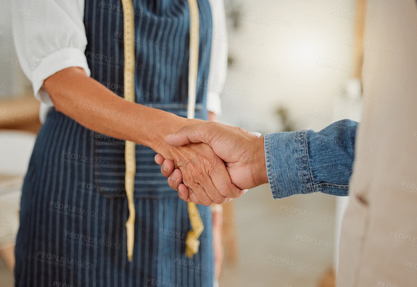 Buy stock photo Creative, handshake and discussion with client, deal and agreement in workshop, fashion designer and apron. Tailor, holding hands and people in business meeting and collaboration in design studio