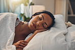 A beautiful young mixed race woman sleeping in a soft comfortable bed at home. One hispanic female feeling exhausted and resting in a comforting bed