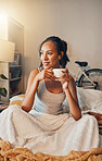 A beautiful young Hispanic woman enjoying a warm cup of coffee for breakfast. One mixed race female drinking tea while sitting in bed and daydreaming