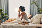 A beautiful young Hispanic woman enjoying a warm cup of coffee for breakfast. One mixed race female drinking tea while sitting in bed and daydreaming