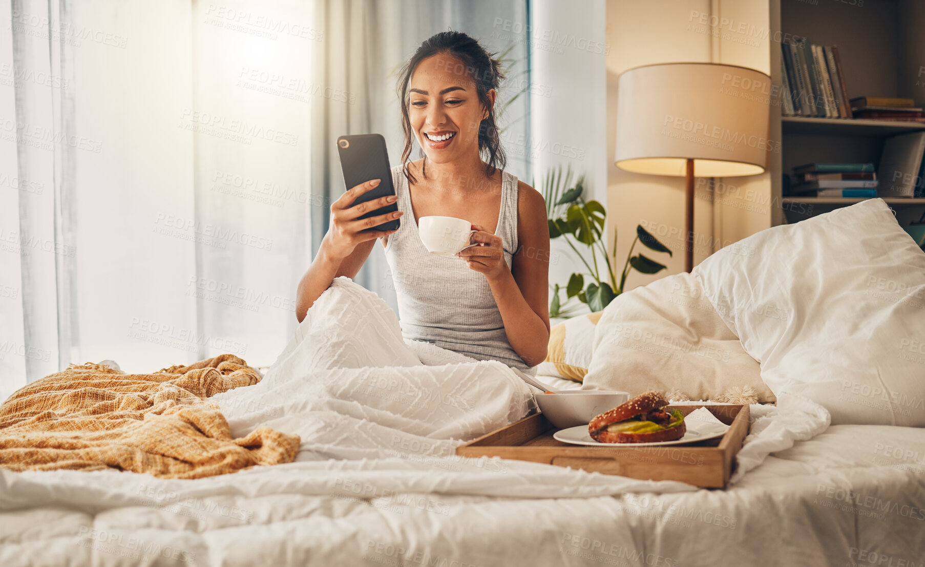 Buy stock photo Breakfast, coffee and happy woman with phone in bedroom for social media, scroll and relax in home. Mobile, girl or drink tea in bed to watch video, reading blog and download app for morning news