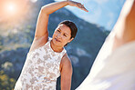 Mature woman stretching her hand over her head while exercising outdoors. Mixed race woman staying fit with yoga classes. Finding inner peace, balance and living healthy