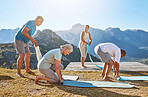 Group of diverse men and women rolling up their yoga mats after a group exercise class in the mountains. Living active and healthy lifestyle