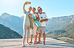 Group of active seniors posing together for a selfie or video call on a sunny day against a mountain view background. Happy diverse retirees taking photo after group yoga session. Living healthy and active lifestyles