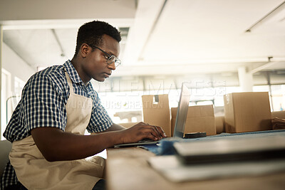 Buy stock photo Small business, black man and typing on laptop as fashion designer for research, creativity and project. Male person, employee and serious at workshop or studio on internet for ordering material