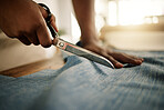 Fashion designer cutting a textile sample. Creative tailor cutting denim fabric with a scissor. Closeup of hands of seamstress cutting material for his design. Business owner working in a studio