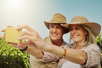 Happy married senior couple taking selfies on cellphone in vineyard. Smiling Caucasian husband and wife standing together and bonding on a wine farm while taking pictures for social media on a phone