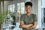 Young happy african american businesswoman standing with her arms crossed alone at work. One cheerful black female boss with an afro smiling while standing in an office