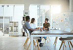 Three young focused businesspeople having a meeting while sitting at a table and at work. Business professionals talking and planning in an office together