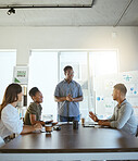 Group of cheerful diverse businesspeople having a meeting in an office at work. Young african american businessman talking while doing a presentation at a table for coworkers