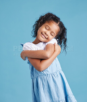 Buy stock photo Self love, happy and child with hug in studio for sweet, embrace and development by blue background. Innocent, smile and little girl kid with gesture of care for affirmation, comfort and kindness