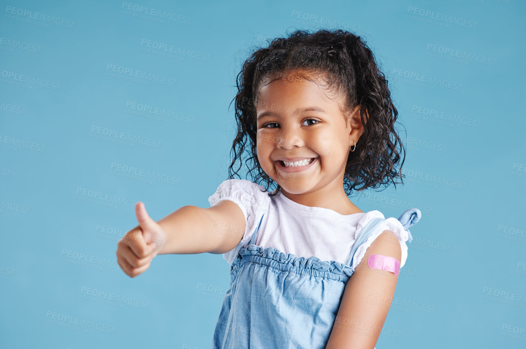 Buy stock photo Thumbs up, plaster and portrait of child in studio for injection, vaccine or medical booster shot. Happy, healthcare and girl kid from Mexico with bandage on arm for immunization by blue background.