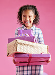 A pretty little mixed race girl with curly hair holding a stack of wrapped presents against a pink copyspace background in a studio. African child looking excited about getting gifts for her birthday