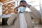 African american male on a phone call with his mobile device inside a station during the day while wearing a mask. Young black male talking on a phone while commuting in a train station and looking stressed