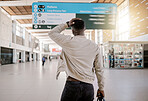 Rear view of African american businessman travelling alone and standing in a train station while looking at his travels times and looking worried