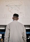 Black man looking at a map while travelling in a station. Reading a map for guidance and directions