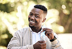 Portrait of a young businessman standing in the street in the city smiling and looking happy on a sunny day. African american male expressing happiness on his face