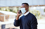 Black businessman wearing a face mask and talking on a cellphone outdoors. Making a call while commuting during the covid pandemic 