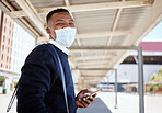 Black businessman travelling alone. A young african american businessman waiting for a train at a railway station and using his wireless cellphone during his commute at a train station