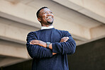 Closeup of a young businessman standing  with arms crossed in the street in the city smiling and looking happy on a sunny day. African american male expressing happiness on his face