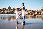 Full length portrait of young african american parents holding hands while carrying their two children and taking a walk along the beach. Young family with little daughter and son spending time together and enjoying vacation