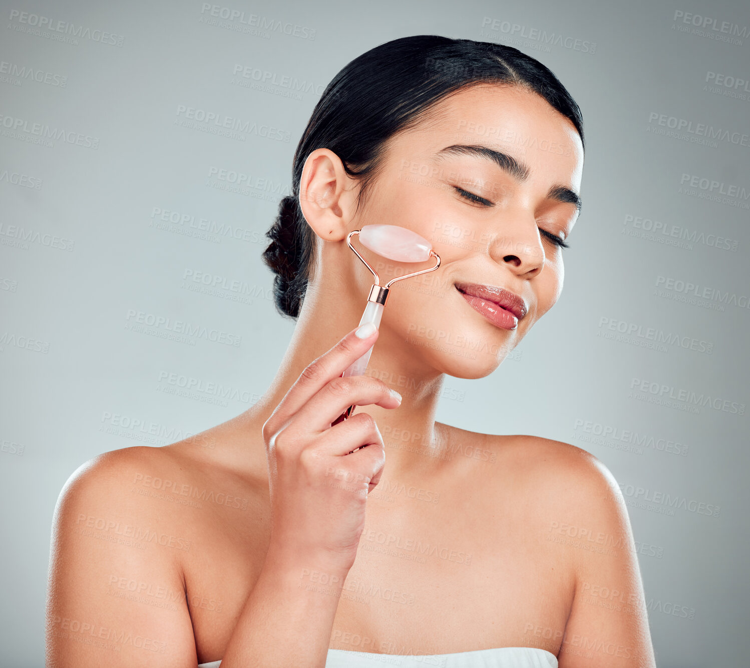 Buy stock photo Skincare, beauty and woman with face roller for healthy skin, wellness and treatment. Rose quartz, stone and model with cosmetics for facial massage, glow and dermatology on gray studio background