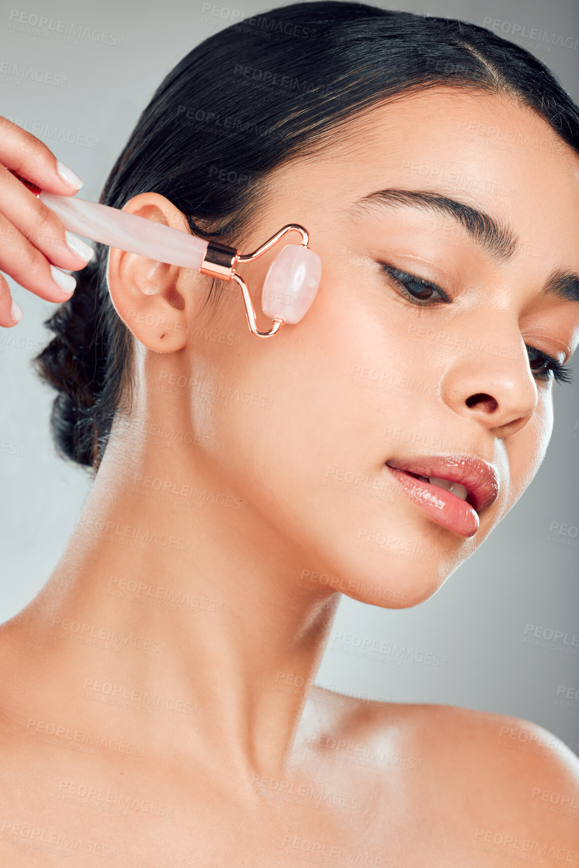 Buy stock photo Skincare, woman and rose quartz roller for beauty, glow and circulation treatment. Face, stone and model with cosmetics for facial massage, wellness benefits and dermatology on gray studio background