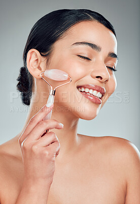 Buy stock photo Skincare, happy woman and face roller for beauty, shine or lymphatic drainage treatment. Rose quartz, stone and model with cosmetics for facial massage, glow and dermatology on gray studio background