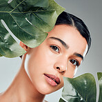 A beautiful mixed race woman posing with a plant. Young hispanic using an organic detox treatment against a grey copyspace background