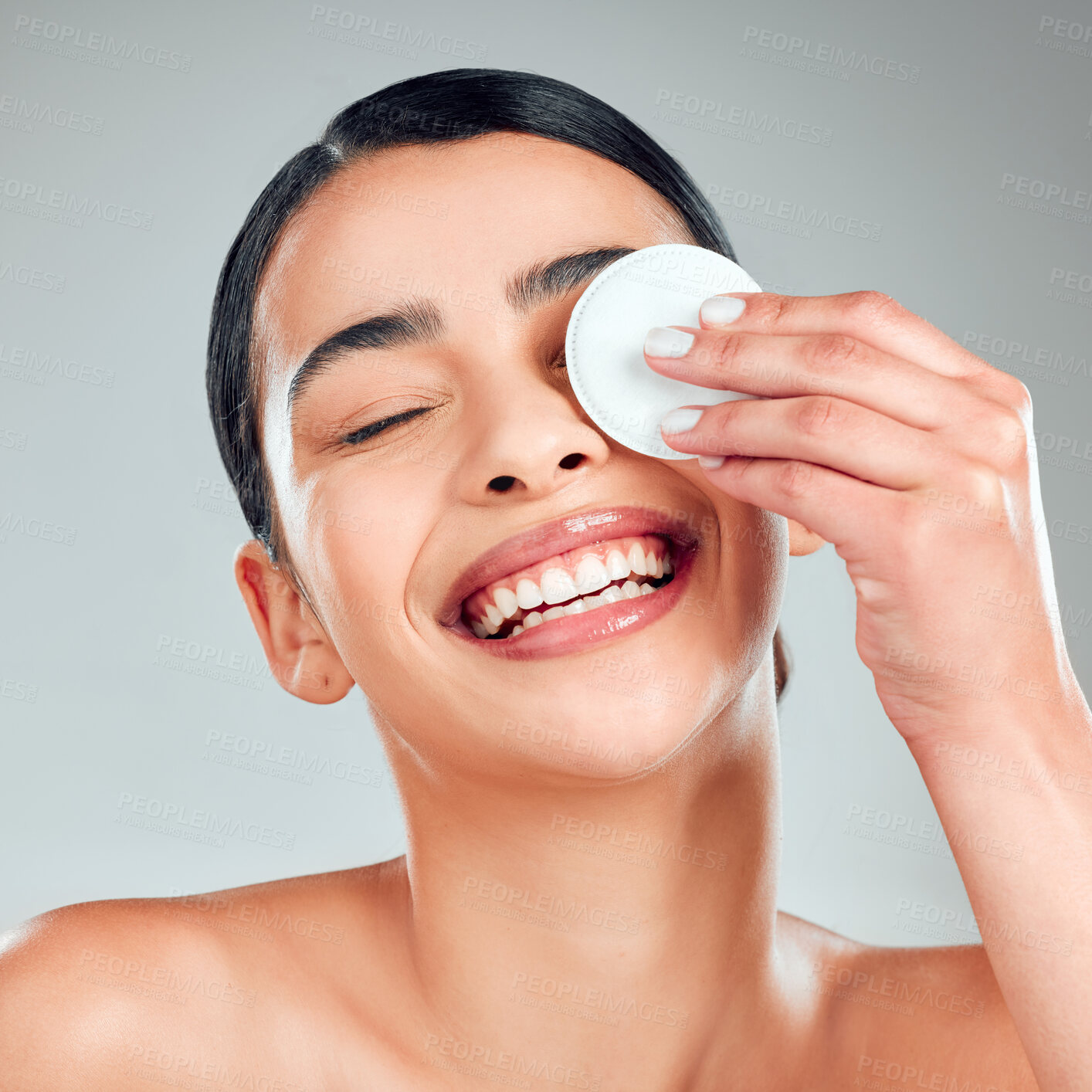 Buy stock photo Happy woman, skincare and beauty with cotton pad for makeup removal on a gray studio background. Young, female person or model with smile or cosmetics for facial cleanse, spa or treatment with patch