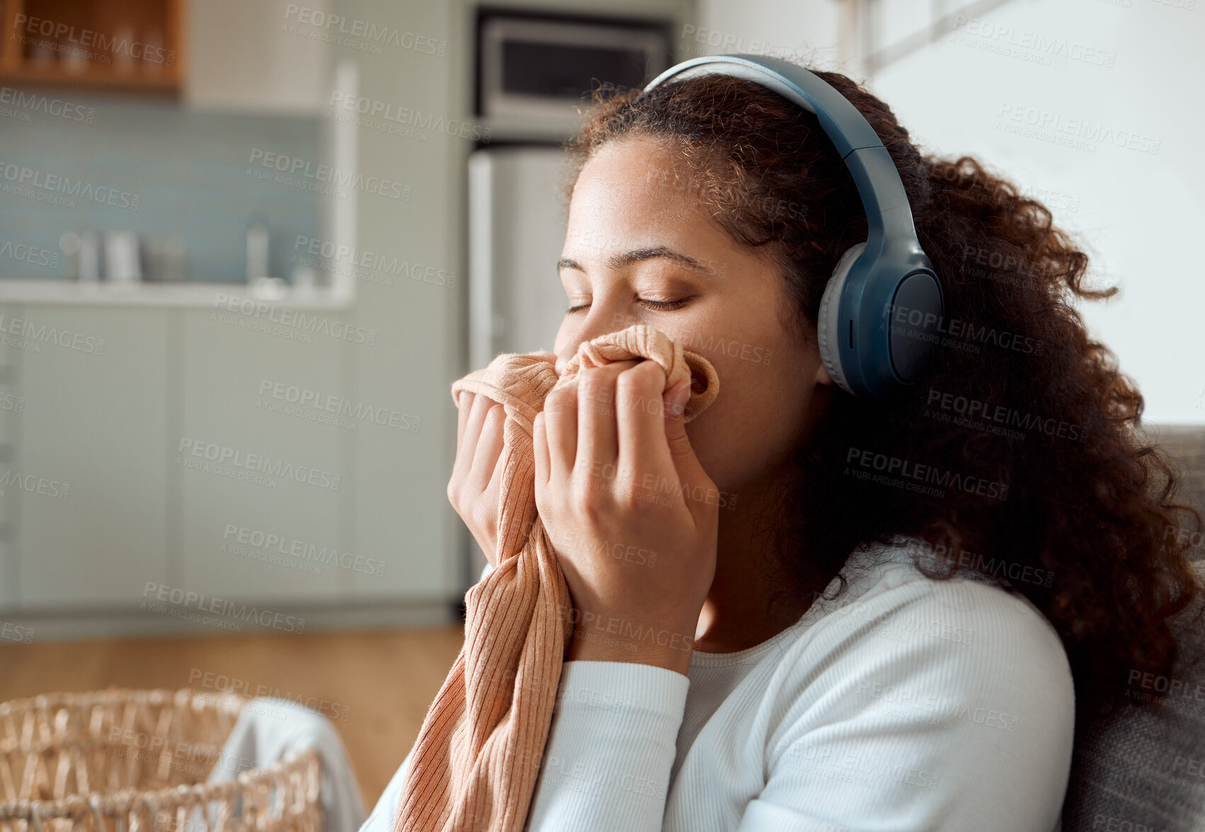 Buy stock photo Woman, headphones and smell laundry in home, clean scent and listening to music in apartment. Female person, washing and inhale aroma of clothes or fresh cotton, cleaner and hearing sound or audio