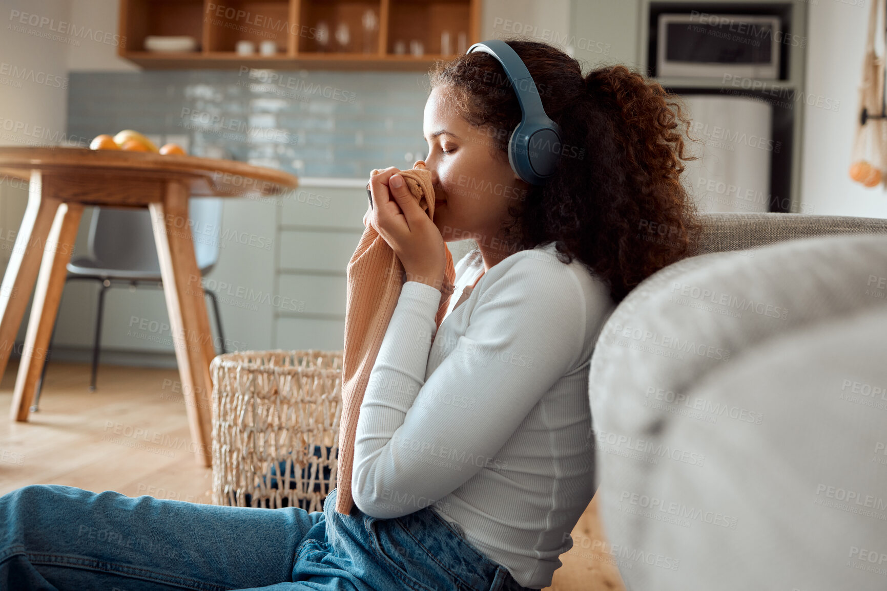 Buy stock photo Woman, headphones and smell clothes in home, clean scent and listening to music in apartment. Female person, washing and inhale aroma of material or fresh laundry, cleaner and hearing sound or audio