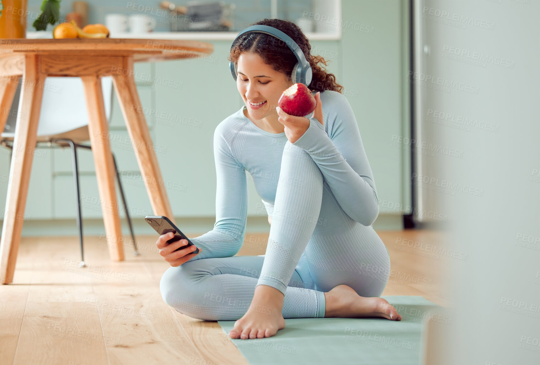 Buy stock photo Woman, phone and headphones with apple and yoga mat with online fitness routine and tutorial in home. Workout, exercise and internet with wellness, health and website scroll in living room with smile