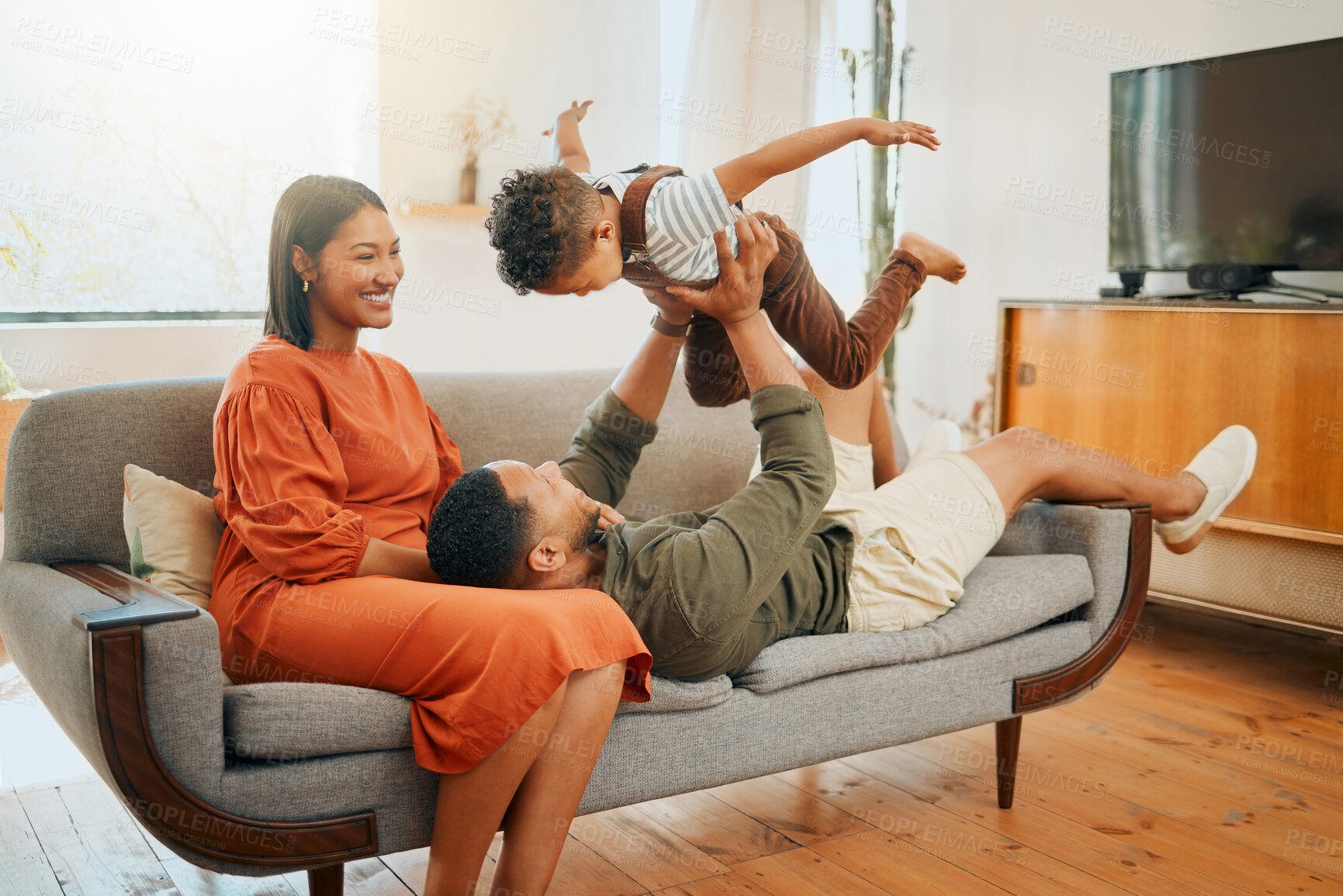 Buy stock photo Funny, airplane and bonding with family on sofa for love, playful game and happiness together. Care, energy and laughing with parents and child in living room at home for silly, comedy and support